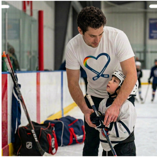 Man is wearing the heart hockey logo t-shirt while teaching a child ice hockey on an indoor rink.