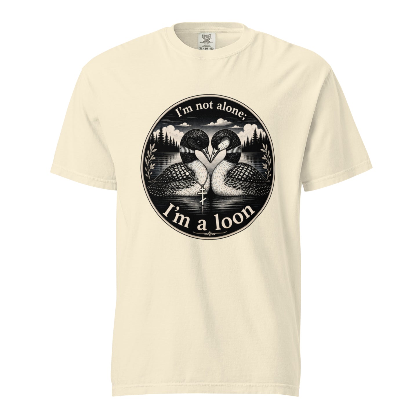 An Ivory colored short-sleeve crewneck t-shirt featuring a circular black and white graphic of two loons facing each other in front of a lake and mountains, with the text 'I'm not alone. I'm a loon'.