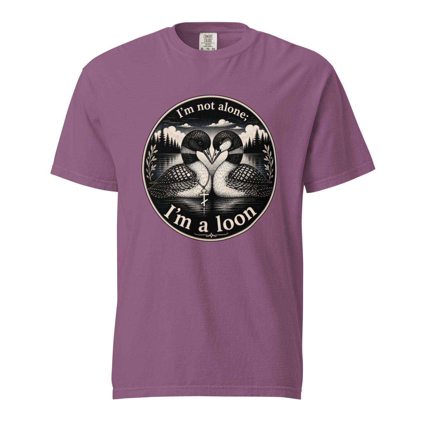 A Berry colored short-sleeve crewneck t-shirt featuring a circular black and white graphic of two loons facing each other in front of a lake and mountains, with the text 'I'm not alone. I'm a loon.