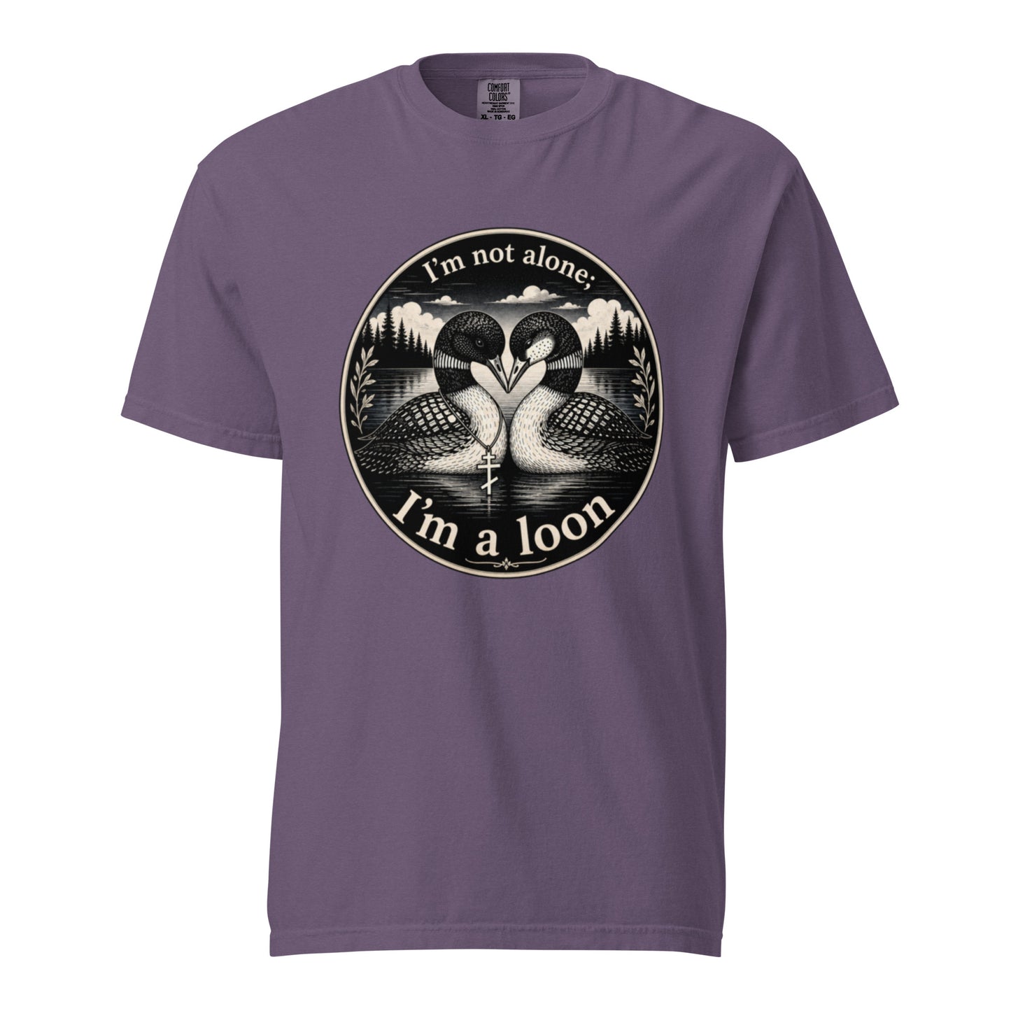 A Grape colored short-sleeve crewneck t-shirt featuring a circular black and white graphic of two loons facing each other in front of a lake and mountains, with the text 'I'm not alone. I'm a loon'.