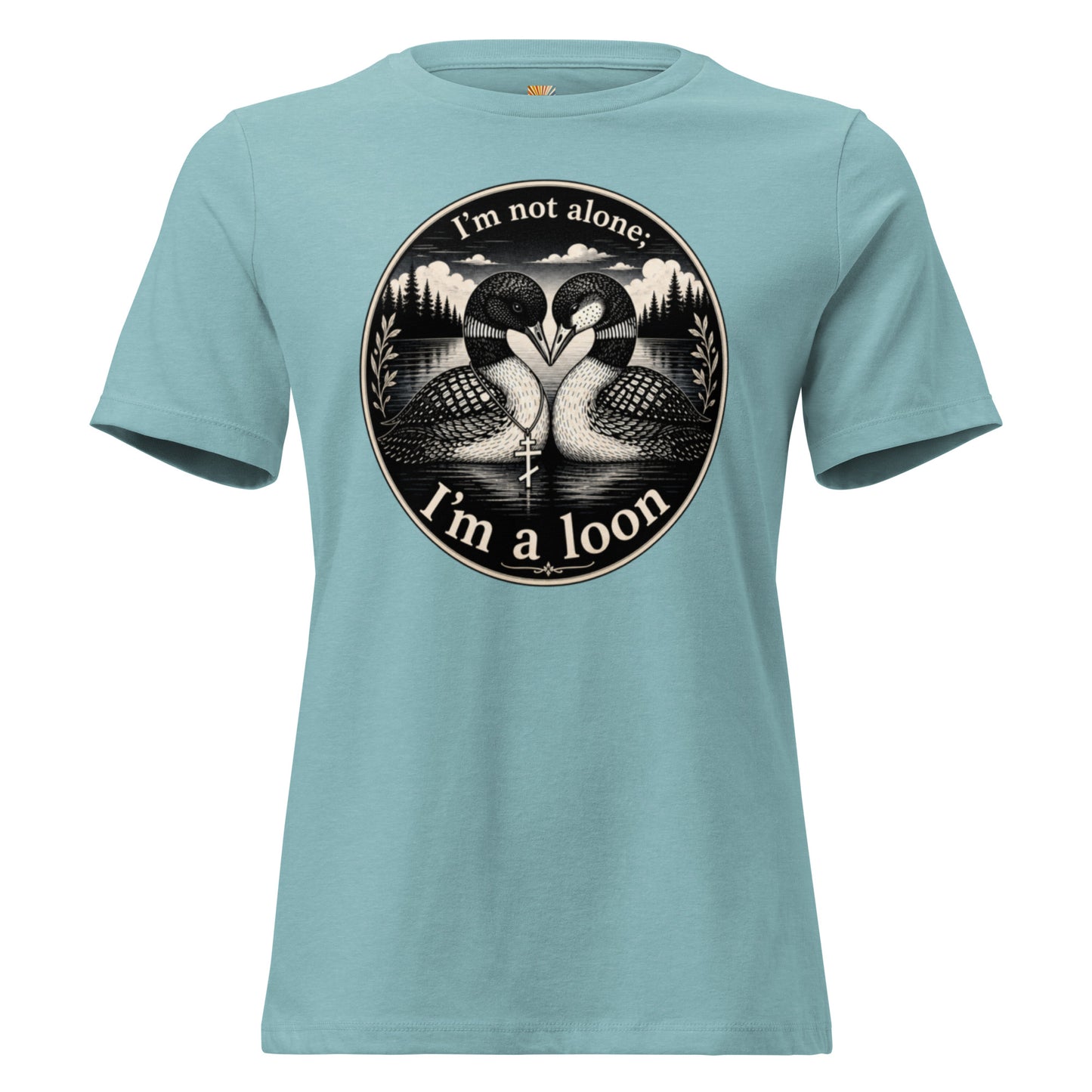 A graphic tee for women in heather blue  lagoon featuring a circular black and white graphic print of two loons facing each other, with the text 'I'm not alone; I'm a loon' arched above and below the illustration.